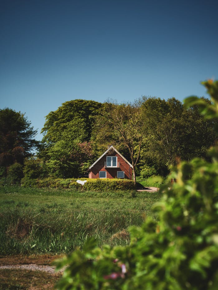Serene view of a red brick house nestled in lush greenery, perfect for a peaceful getaway.